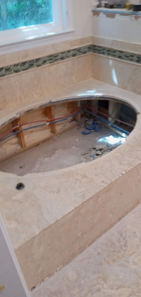 Jetted tub demolition — plumbing exposed, marble surround removed